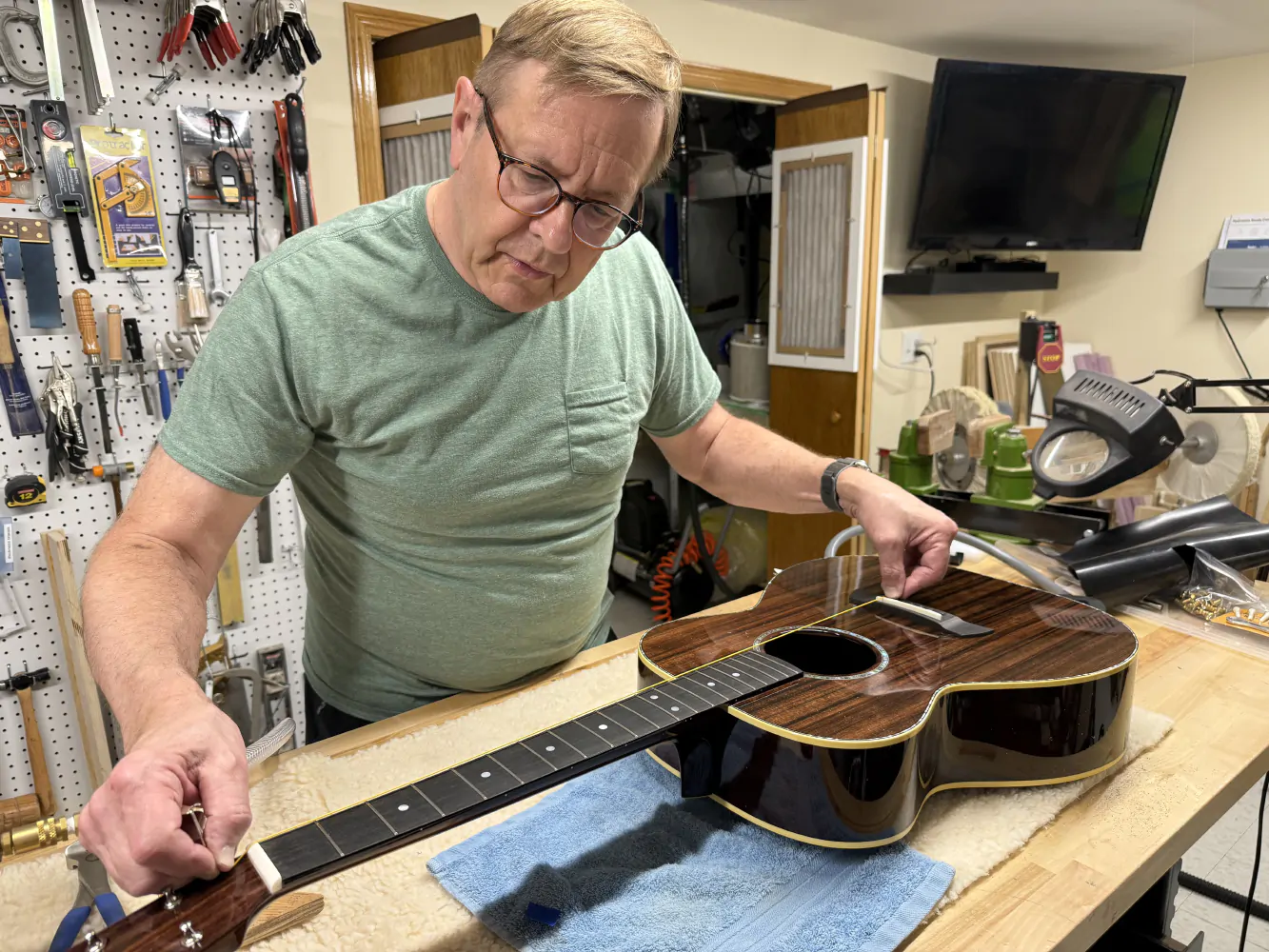Robert Mizek at work in his guitar shop, restringing his newest instrument.